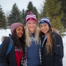 Three female Northland Community and Technical College students stand outside on campus sporting their NCTC gear.