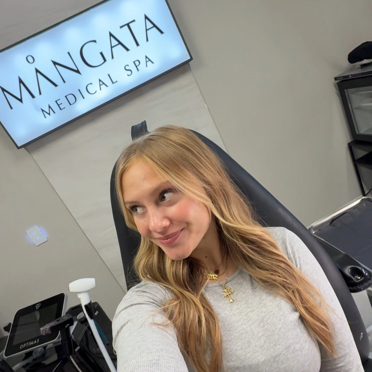 WCT author Isabelle takes a selfie in a chair with a sign behind her that reads "Mangata Medical Spa"