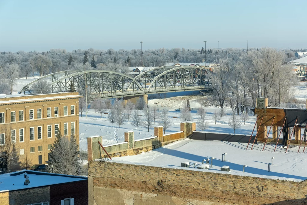 An image taken from atop a parking ramp building in downtown grand forks. Overlooks the bridge leading into downtown with the hoarfrost from winter encasing the scenery.