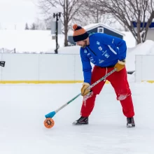 Winter activities in Grand Forks are fun. This image is a man playing broomball in the winter in downtown Grand Forks.