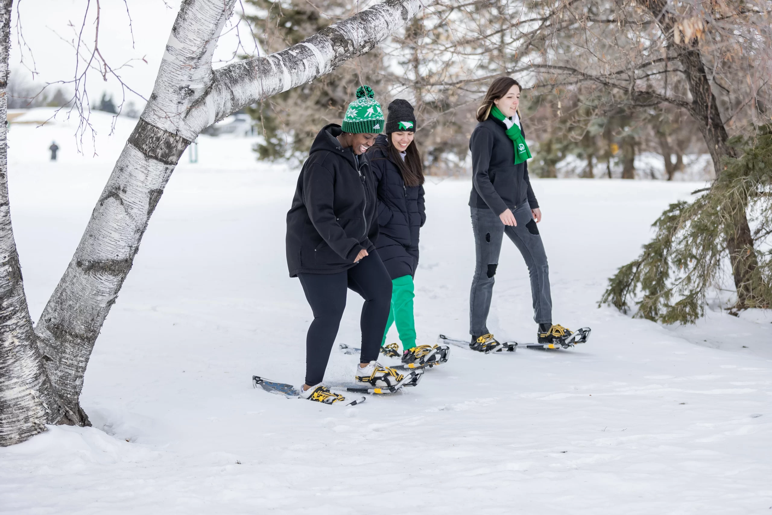 Gon and her friends snowshoeing through trees dressed in winter gear.