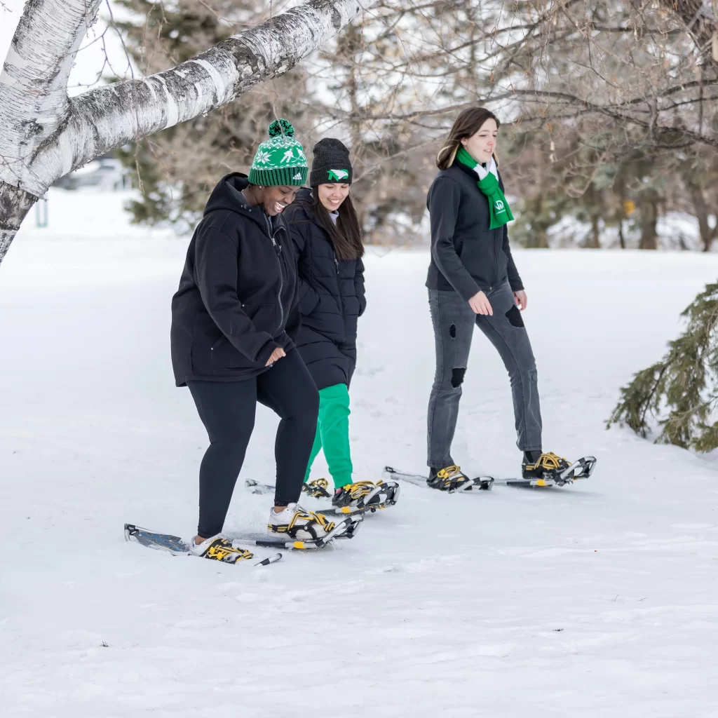 Gon and her friends snowshoeing through trees dressed in winter gear.