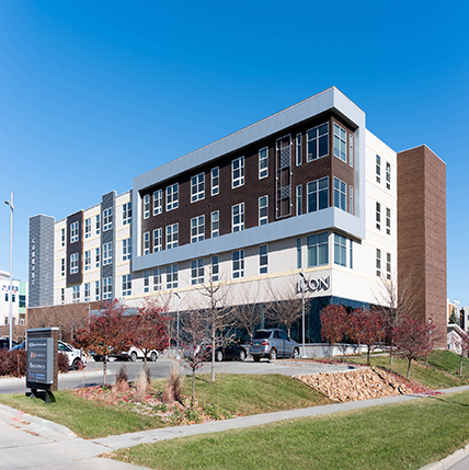 Exterior Photo of 42nd St Commons. The building has grey, brown, and white colors spread out into sections across the facade.