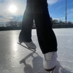 Author Kinley poses for a close up of her skates. The sun is shining behind her so it lights up the image.