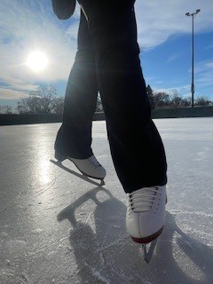 Author Kinley poses for a close up of her skates. The sun is shining behind her so it lights up the image.