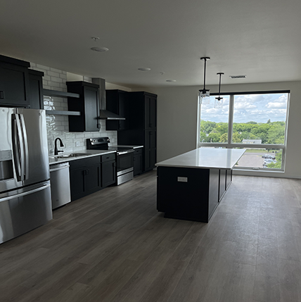 Interior of Spirit at the Beacon kitchen. Black cabinets and silver appliances with a floor to ceiling window. White tile backsplash.