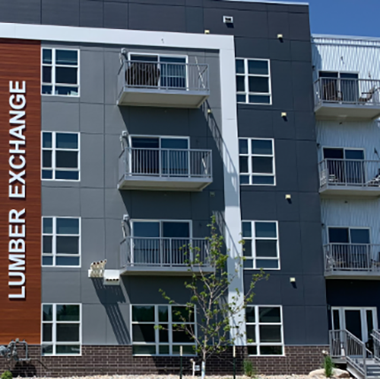 Exterior of Lumber Exchange apartments. Gray siding with loads of small windows and small balconies as well.