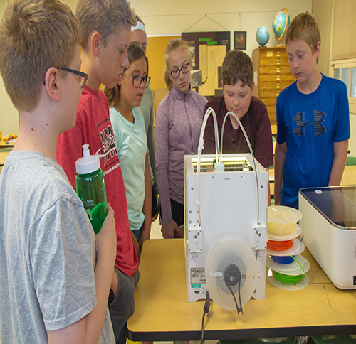 A group of seven kids stand around a project they've been working on at engineering camp