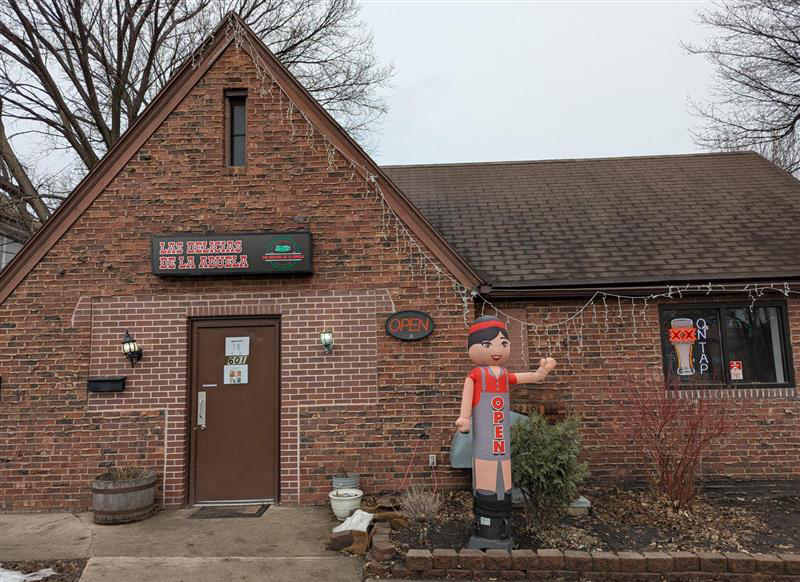 Restaurant Photo Adrian Outdoor photo of Las Delicias de la Abuela in Grand Forks. A small red and brown brick building with an statue of what looks like "Abuela" outside the front.