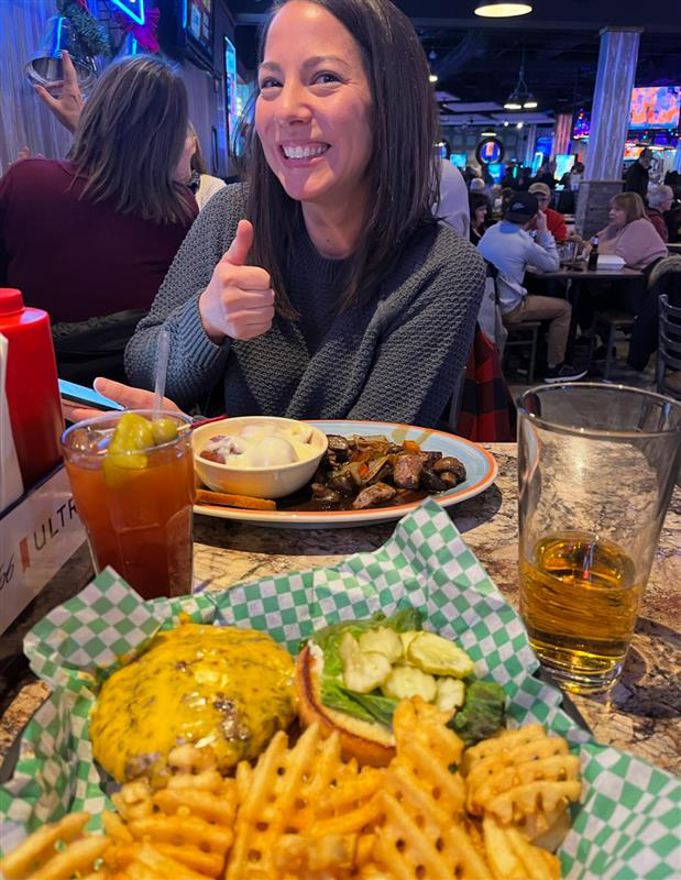 Author Bru's wife poses with a thumbs up for the camera as their freshly served plates are on the table for date night!