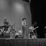 Author Adrian attends a grand forks Empire Theater concert. A country band performs on the stage and the image is in black and white.