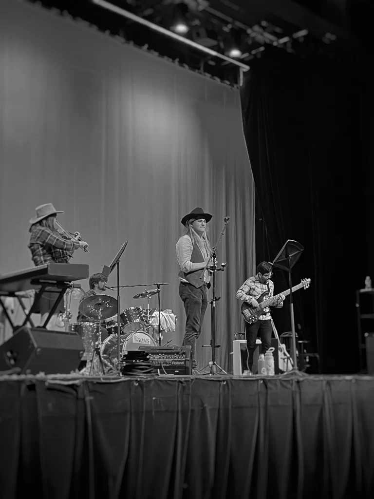 Author Adrian attends a grand forks Empire Theater concert. A country band performs on the stage and the image is in black and white.