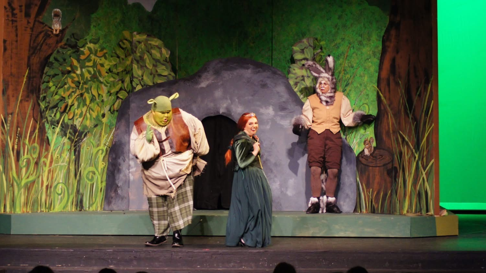 Photo of the Shrek musical in Grand Forks. Fiona, Shrek, and Donkey sing together on stage.