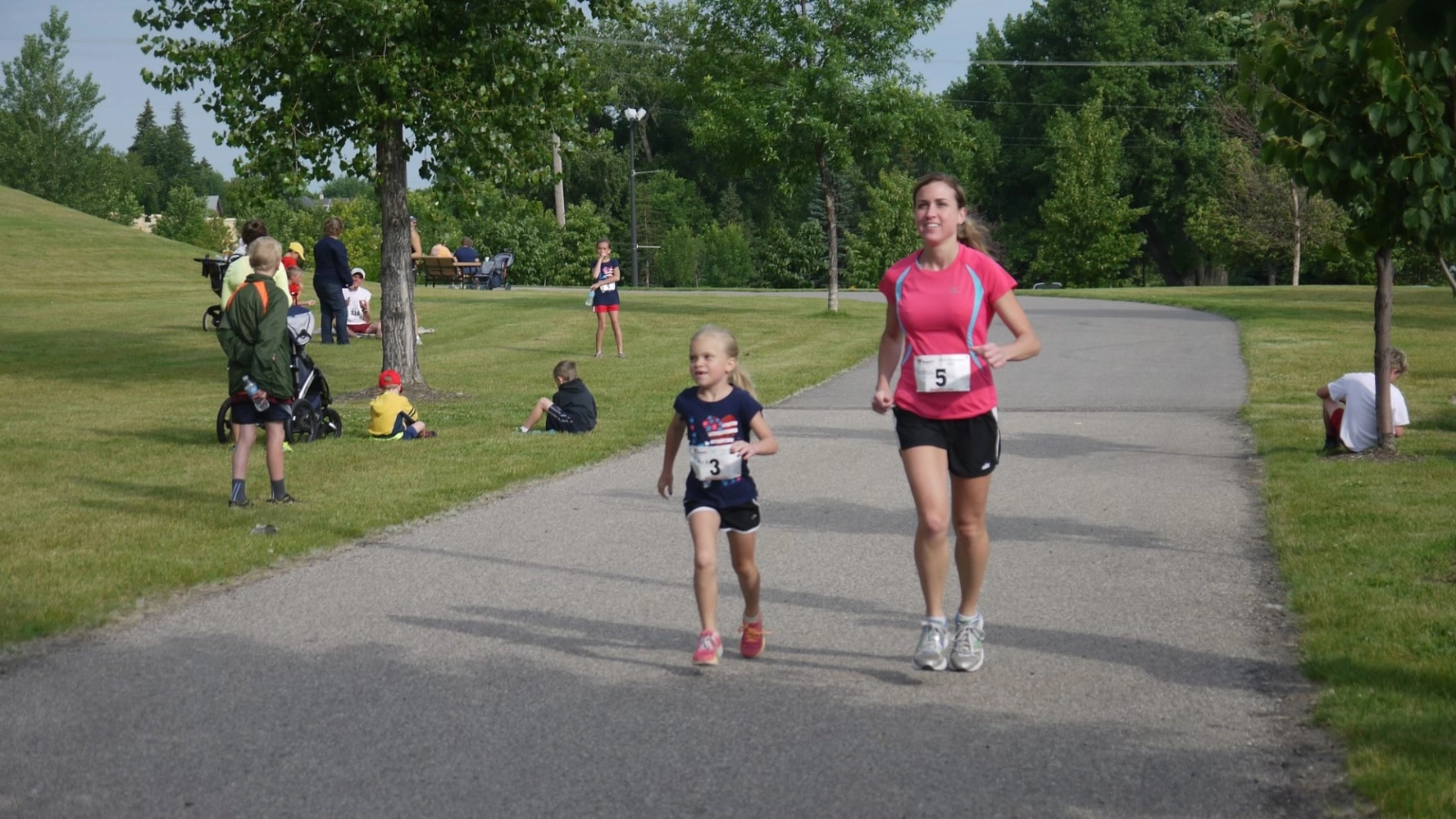 A mother and daughter run side by side in a race through Grand Forks Greenway