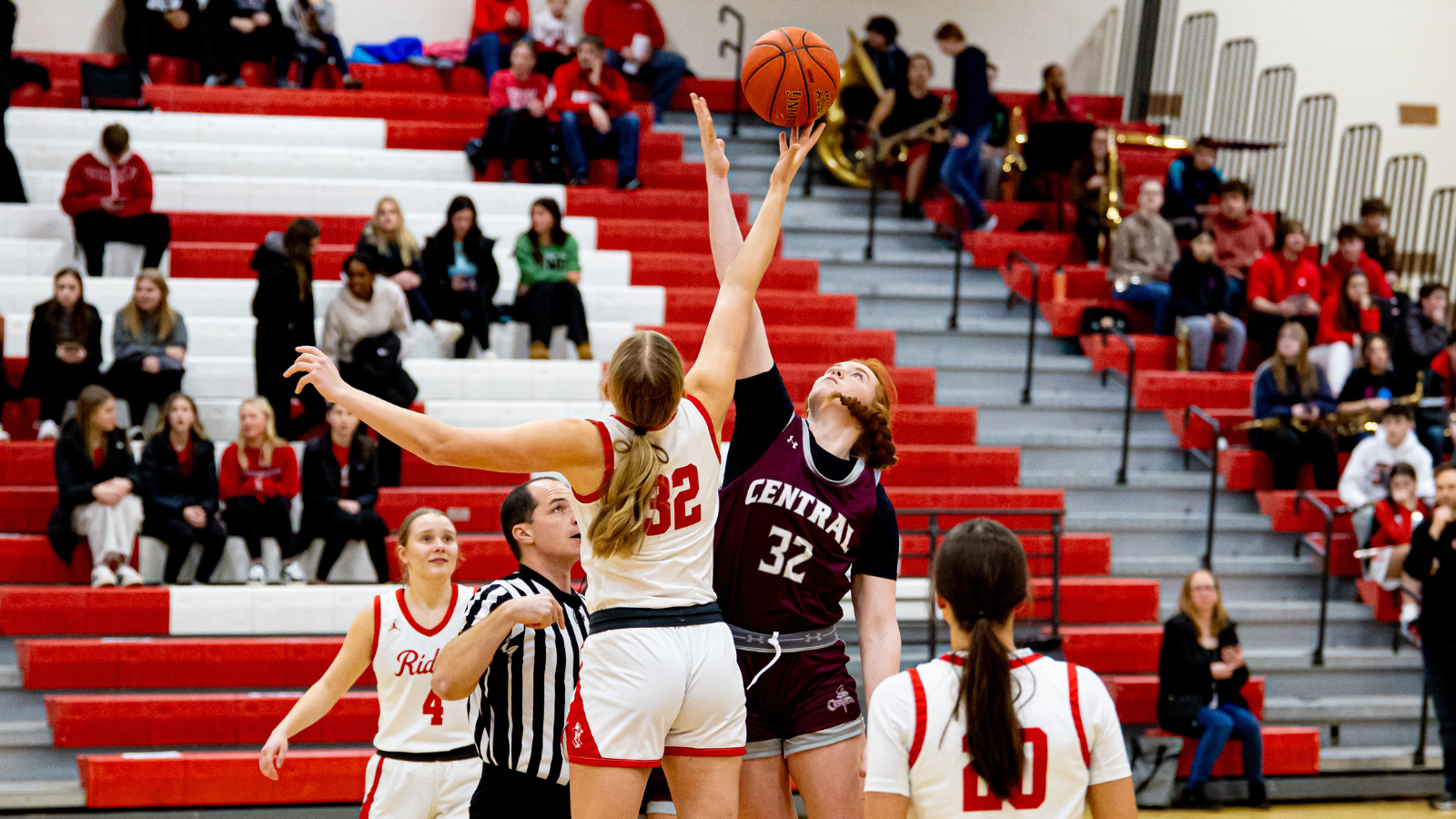 A girls basketball game, two players tip-off the ball.