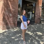 author Natalie poses in front of the Urban Stampede coffee spot