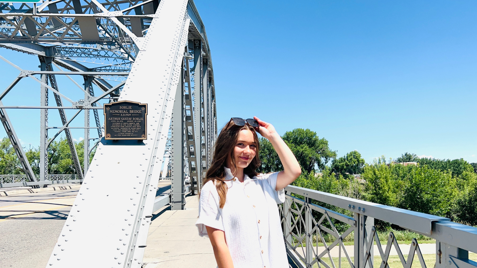 Author Natalie poses from the waist up at the start of the ND side of the Sorlie bridge, smiling in the sunshine.
