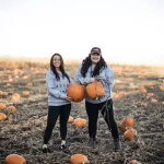 Holding pumpkins in a field in grey sweatshirts!