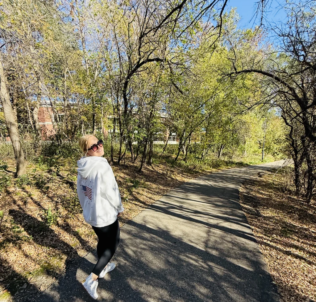 Author Lauren looks back and smiles at the camera on the path on the Greenway during the fall season