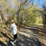 Author Lauren looks back and smiles at the camera on the path on the Greenway during the fall season