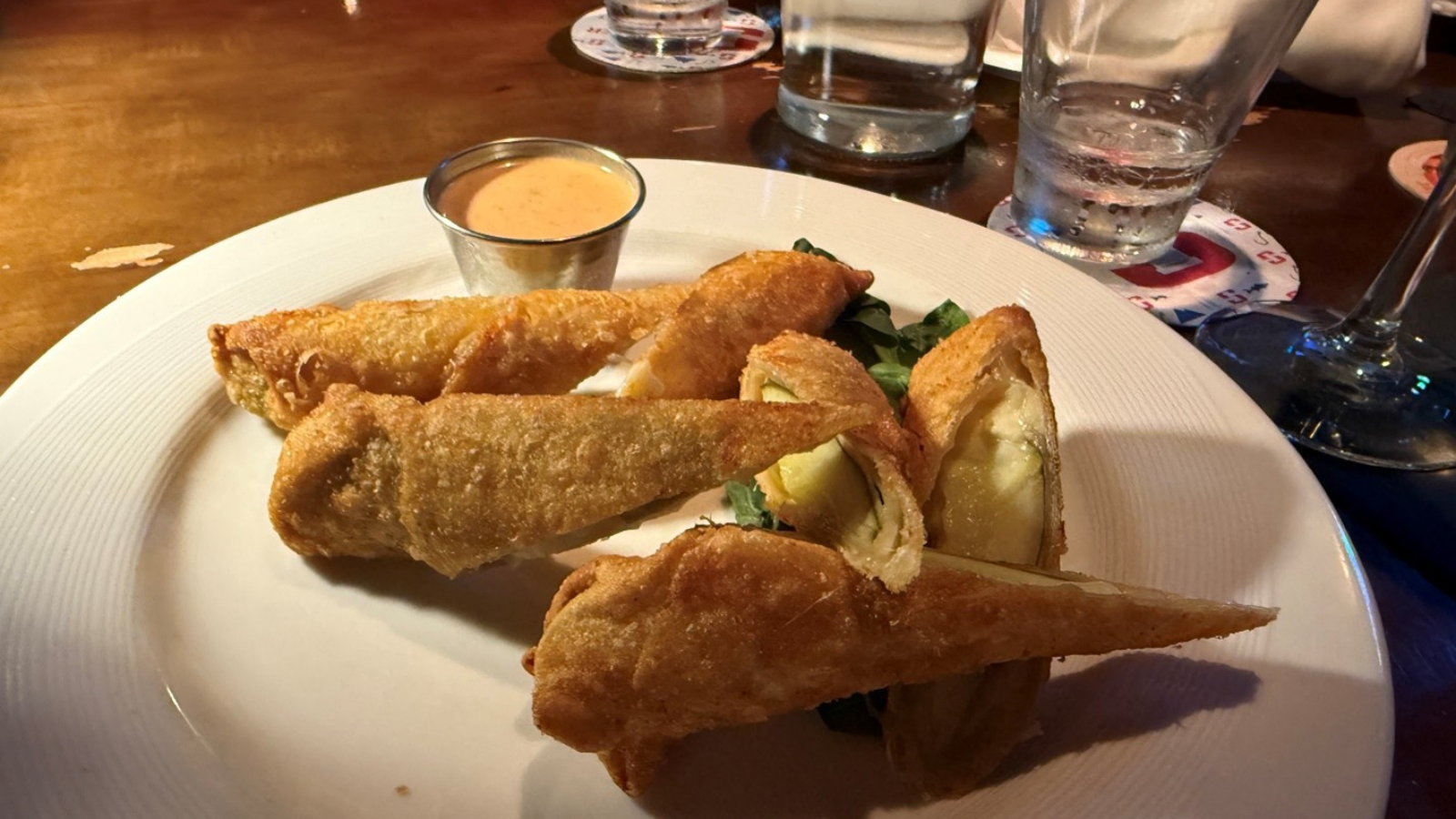 Toasted Frog's fried cheesy pickle spears wait to be devoured on a plate with some mouthwatering aioli sauce.