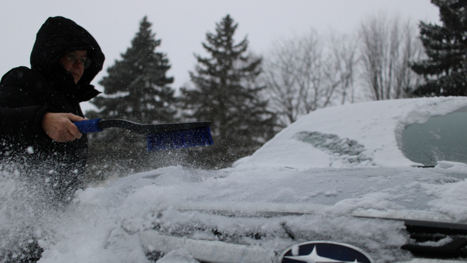 Author Eli's friend brushes off the hood of her car with a snow brush/ice pick dual. Very handy!