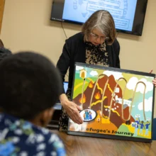 Global Friends Coalition Photo Featured image shows a representative from Global Friends Coalition showing a group of volunteers the refugee's journey via a diagram.