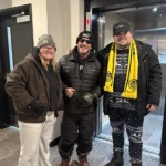 Emma stands with two moving helpers inside new apartment complex