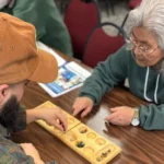 Featured image of a young man playing a board game with an elderly woman