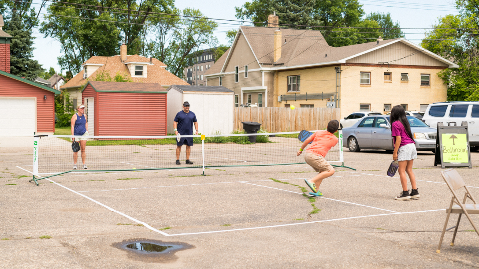 Pickleball Photo A group of four people of different ages play pickleball on a concrete court together in Grand Forks