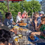 A group sits down for some pizza and grub on the Rhombus Pizza rooftop patio in the summertime!