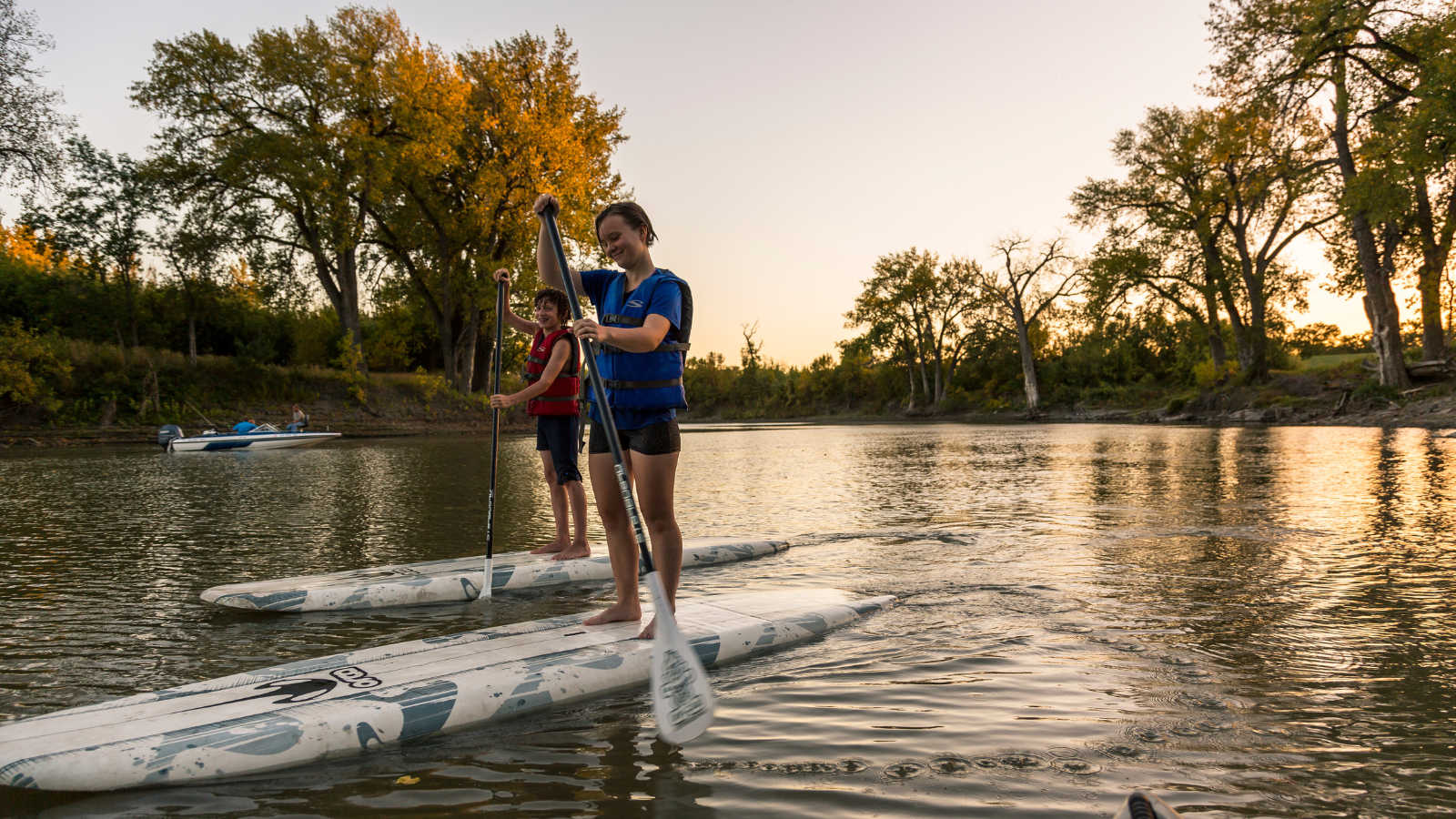Two young Grand Forksians paddle board during golden hour on the Red River