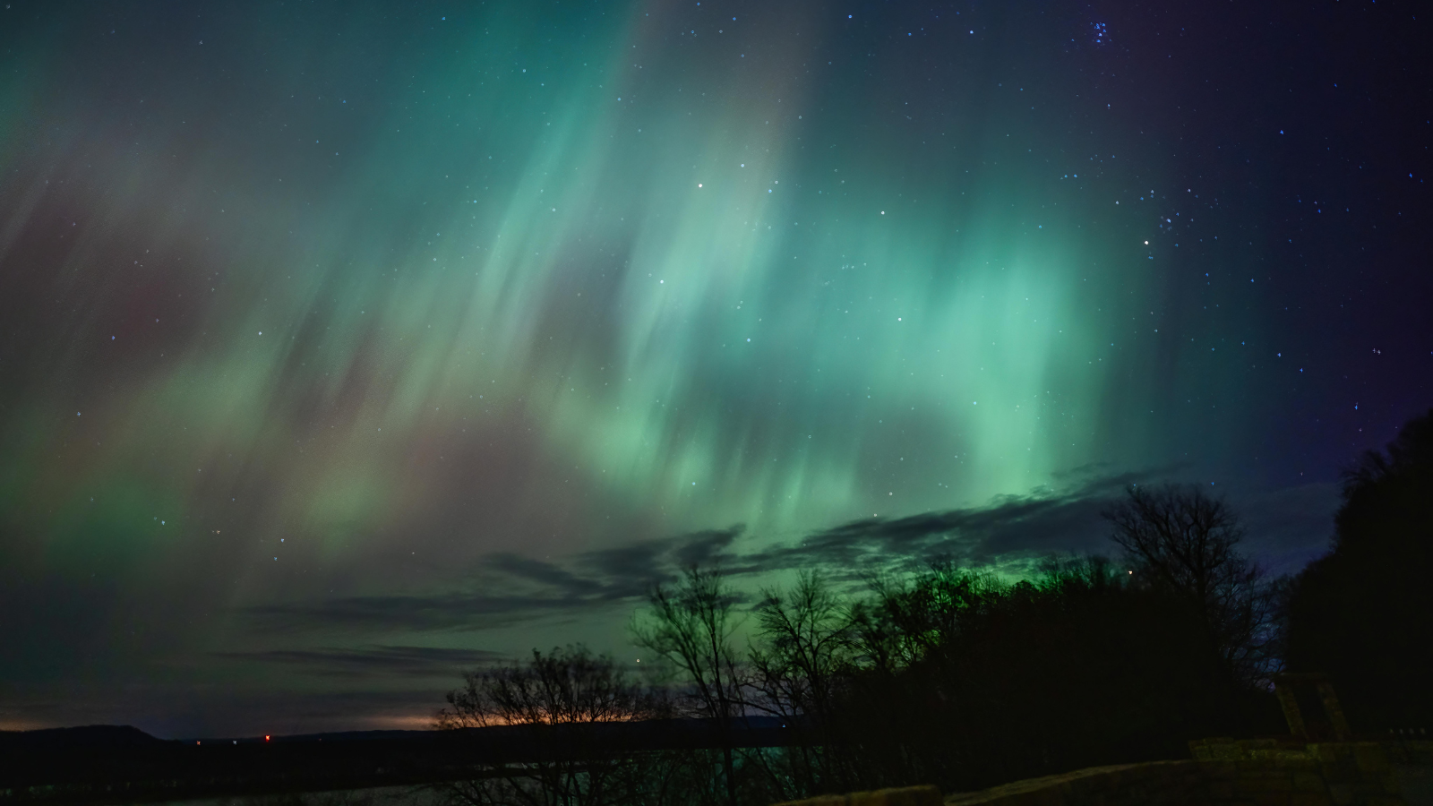 Green and blue northern lights shine across a field in the red river valley